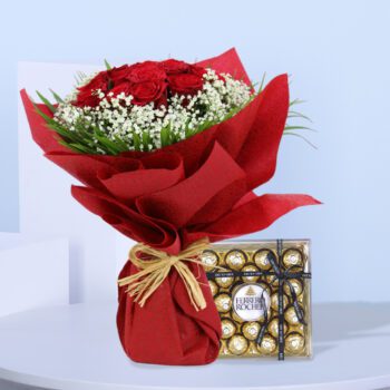 A bouquet of red roses and white baby's breath next to a box of Ferrero Rocher chocolates