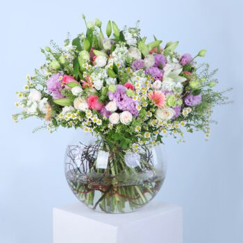 Pink gerberas, pink roses, white ohara lilies, tanacetum, bublurium, white lilies, mathiola, purple lisianthus, and white baby roses in a glass vase.