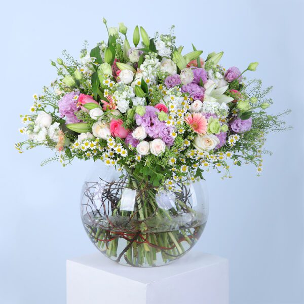 Pink gerberas, pink roses, white ohara lilies, tanacetum, bublurium, white lilies, mathiola, purple lisianthus, and white baby roses in a glass vase.