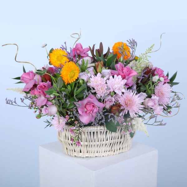 A decorative basket overflowing with colourful flowers is displayed on a pedestal, highlighting its natural beauty and charm.