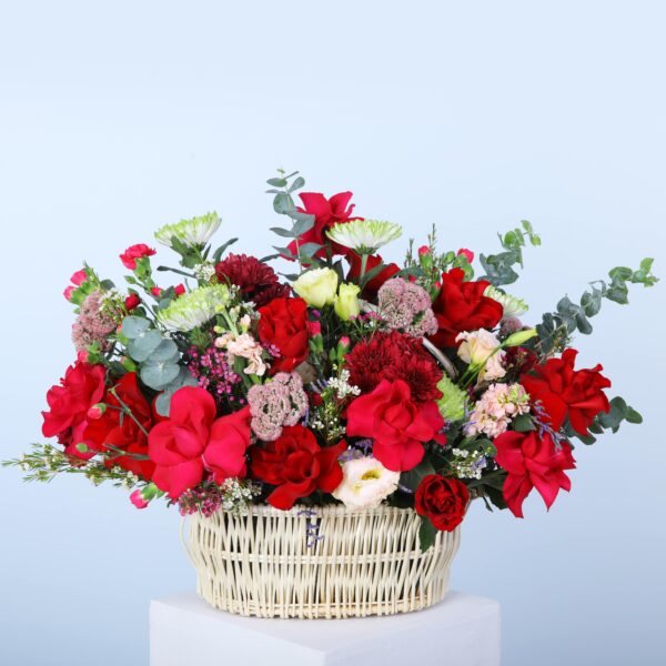 A flower Basket of mixed shades of flowers, featuring roses, carnations, lisianthus, wax flowers, and eucalyptus