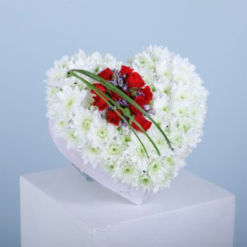 A heart-shaped floral arrangement with white and red flowers.