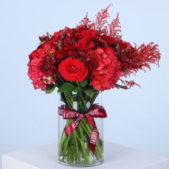 A clear glass vase filled with vibrant red flowers, adding a pop of colour to any event.