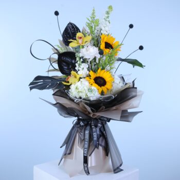 A bouquet featuring bright sunflowers and deep black leaves, artistically arranged on a pedestal for a striking effec