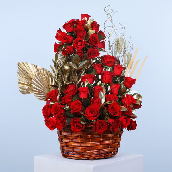 A luxurious arrangement of 50 red roses with golden leaves and accents. in a wicker basket.