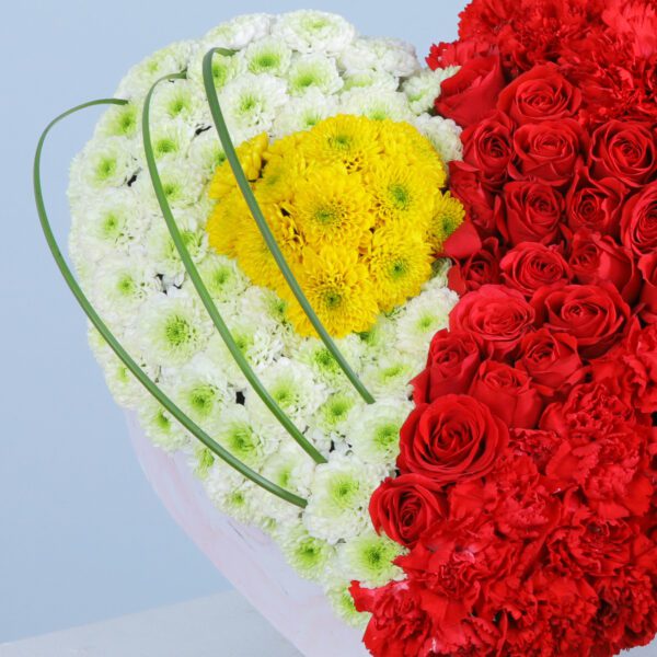 A striking heart-shaped arrangement split into sections of white chrysanthemums and red carnations for a stunning visual effect.