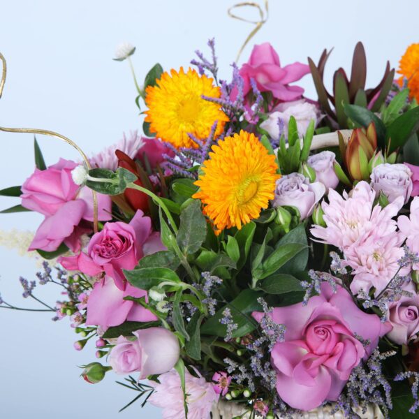 A charming basket filled with vibrant flowers displayed on a pedestal, enhancing its natural beauty and elegance.