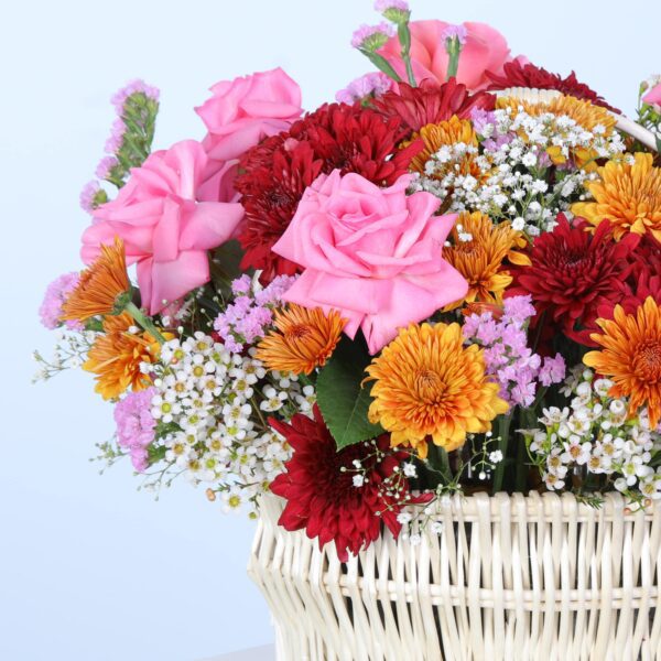 A colourful mix of flowers in a chic basket, elegantly set on a white pedestal.