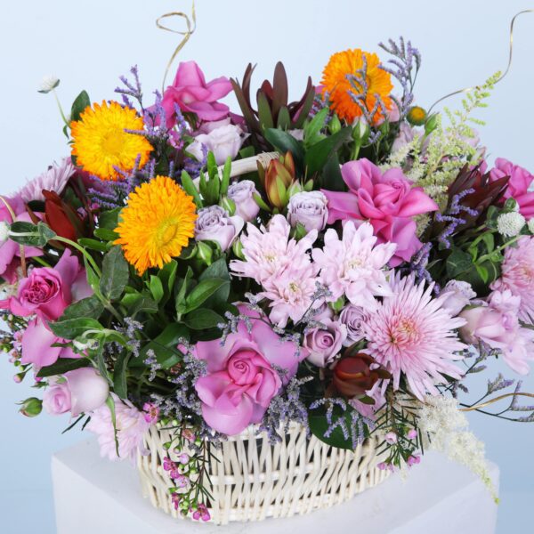 A decorative basket brimming with colourful flowers, elegantly showcased on a pedestal to highlight its natural beauty.