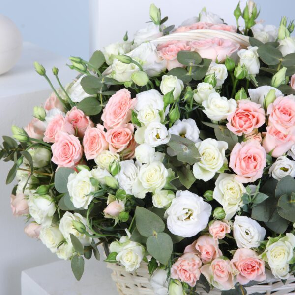 Pastel bloom basket with soft pink Sweet Sara roses, white spray roses, lisianthus, and eucalyptus stems.