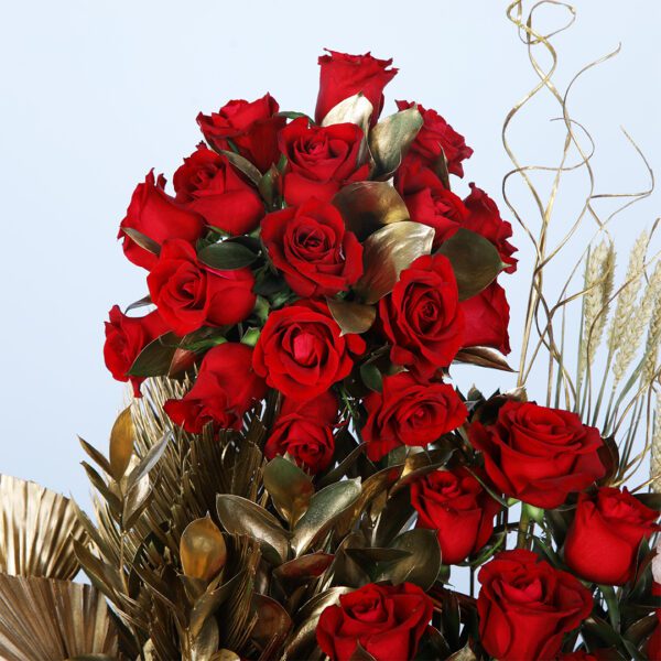 Wicker basket filled with 50 red roses and golden leaf accents.