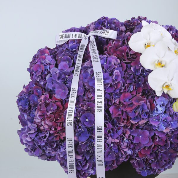 Elegant box of purple hydrangeas accented with Phalaenopsis orchids for a luxurious touch.