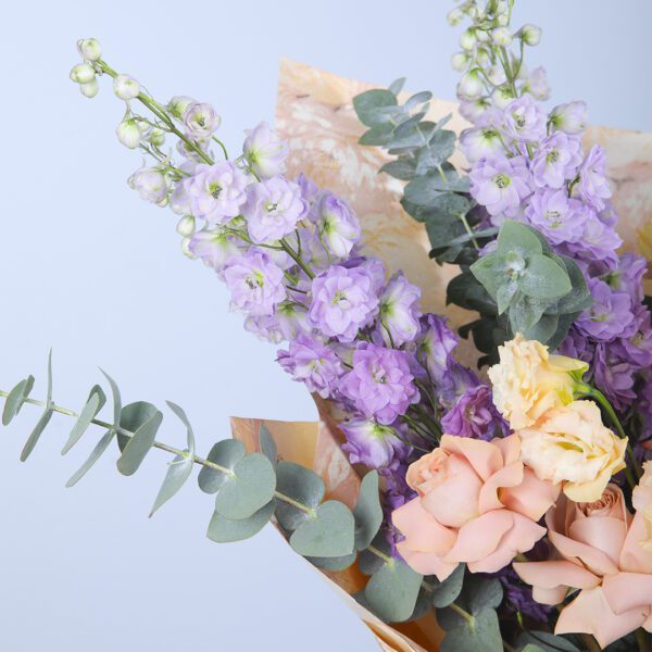 A timeless bouquet of peach roses, delphinium, and lush greenery, perfect for any occasion.