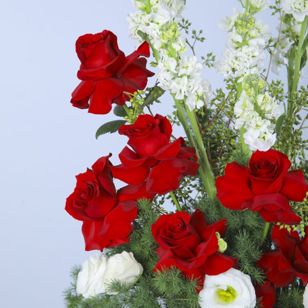 Celebrate a special birthday with this vibrant floral hat box featuring red roses, Mathiolla, and lisianthus, adorned with lush greens.