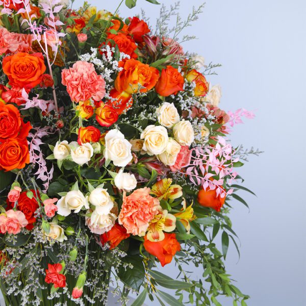 A vibrant floral arrangement featuring a mix of carnations, garden roses, dianthus, and buttercups in a vase.