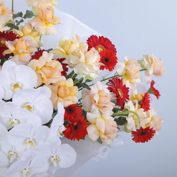 Colorful Floral Arrangement Featuring Peach Roses, White Anthurium, Phalaenopsis Orchids, Red Gerberas, and Greenery