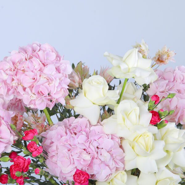 A charming table arrangement of pink hydrangeas and white roses, perfect for a dinner party.