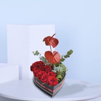 A heart-shaped box filled with red roses and anthuriums, symbolizing love and passion.