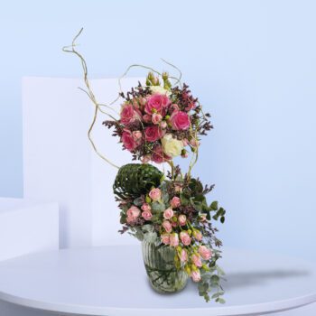 Beautiful flower arrangement featuring vibrant pink roses and lush greenery with decorative accents.