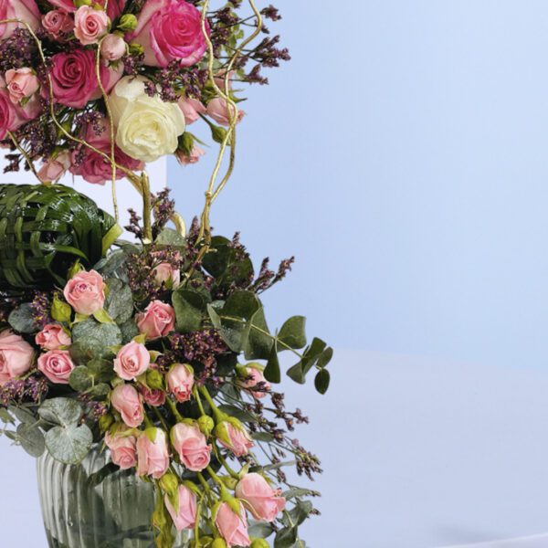 Beautiful flower arrangement featuring vibrant pink roses and lush greenery with decorative accents.