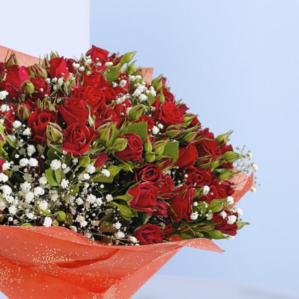 A bouquet of 20 red baby roses with added greenery and gypso wrapped in red paper and tied with black ribbon.