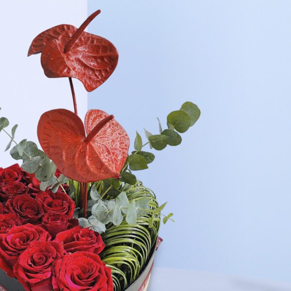 A heart-shaped box filled with red roses and anthuriums, symbolizing love and passion.