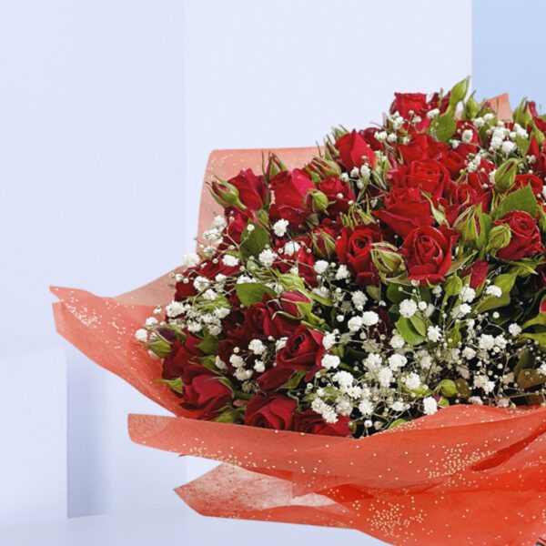 A bouquet of 20 red baby roses with added greenery and gypso wrapped in red paper and tied with black ribbon.