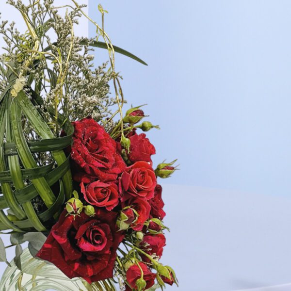 Unique floral arrangement with woven green accents, red roses, and tulips in a glass vase for decor or gifting purposes.