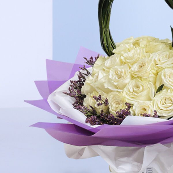 A beautiful arrangement of white roses and purple tulips in a basket with a unique handle.