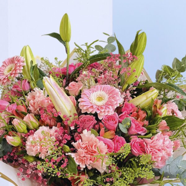 A beautiful bouquet of pink flowers tied up with a white ribbon.