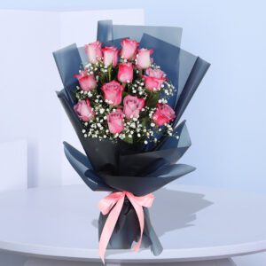 A bouquet of pink roses with baby's breath wrapped in black and pink paper, tied with a pink ribbon